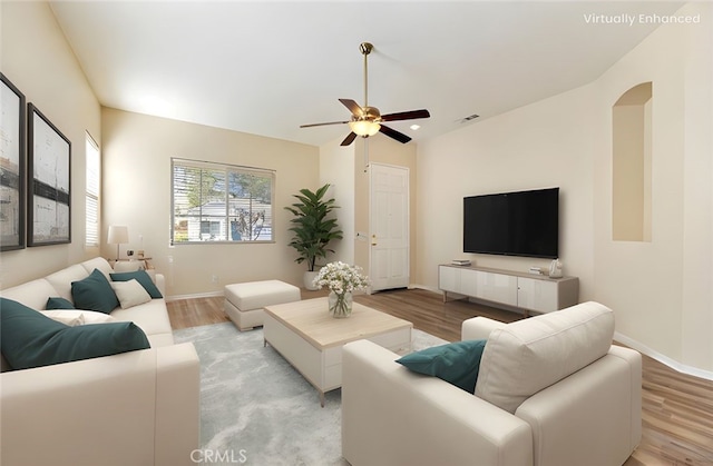 living room with baseboards, arched walkways, ceiling fan, and light wood finished floors