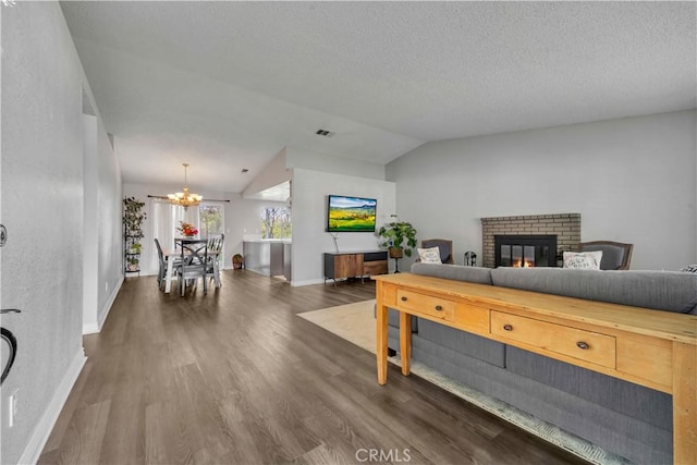 37025 96th St E, Littlerock, CA 93543 - living room with lofted ceiling, baseboards, an inviting chandelier, dark wood-style flooring, and a brick fireplace