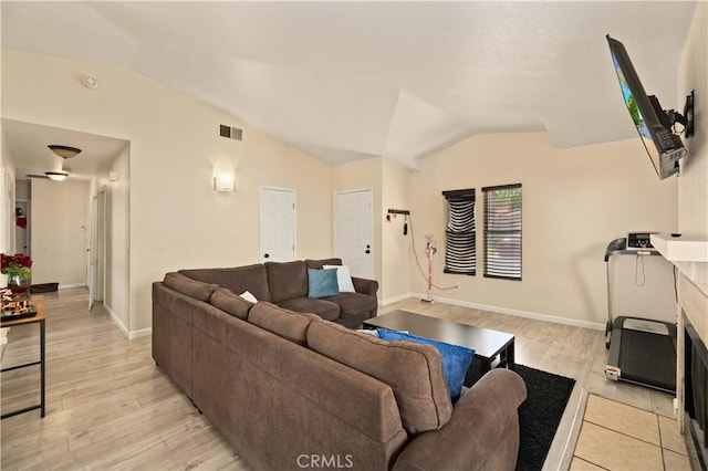 living room with visible vents, baseboards, lofted ceiling, and light wood-type flooring