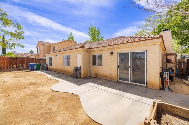 rear view of property with a patio, a tile roof, a chimney, stucco siding, and a fenced backyard