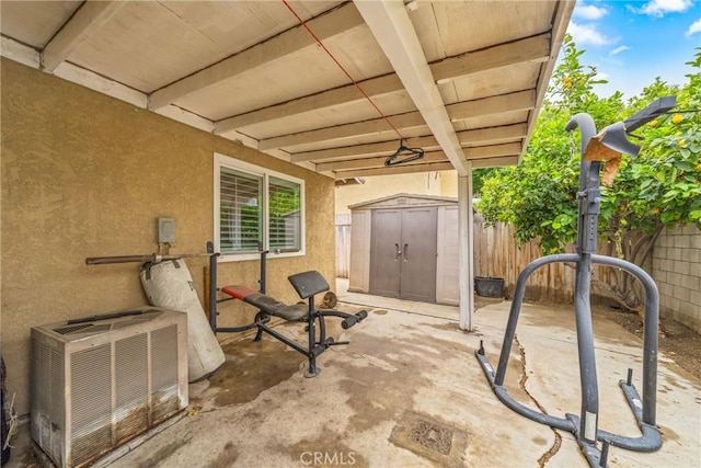 view of patio / terrace featuring fence, an outdoor structure, central AC, and a shed