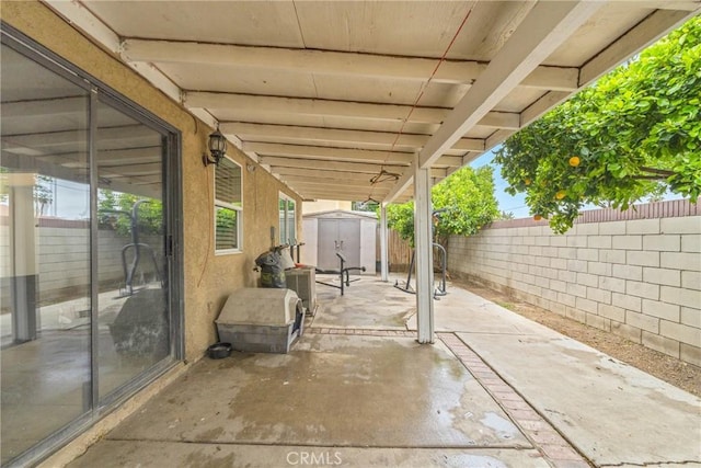 view of patio featuring a storage unit, a fenced backyard, and an outdoor structure