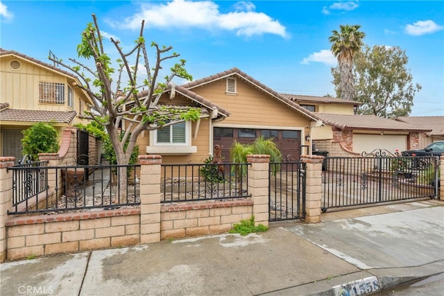 view of front of property with a tiled roof, driveway, a fenced front yard, a gate, and a garage