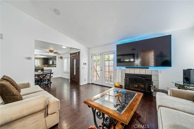 living room featuring ceiling fan, a tiled fireplace, baseboards, wood finished floors, and lofted ceiling
