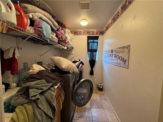 laundry room featuring washing machine and clothes dryer, laundry area, visible vents, baseboards, and tile patterned flooring