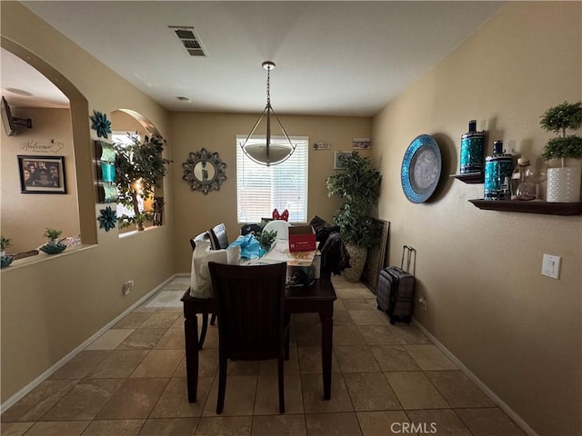 dining space with arched walkways, tile patterned flooring, visible vents, and baseboards