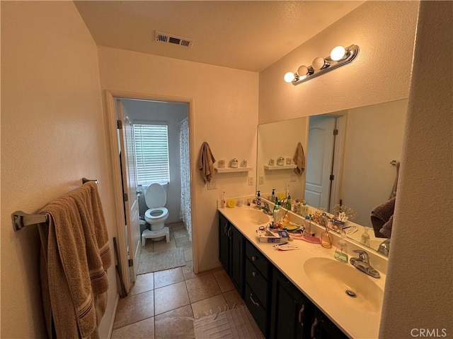 full bath featuring double vanity, visible vents, toilet, and a sink