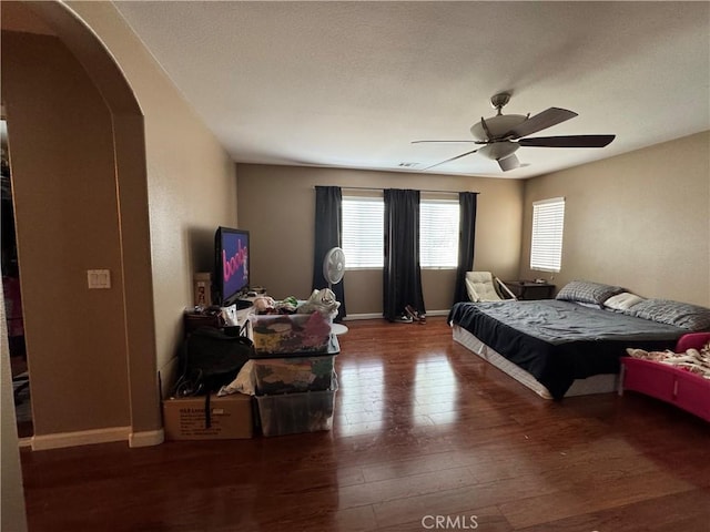 bedroom featuring baseboards, arched walkways, a ceiling fan, and hardwood / wood-style flooring