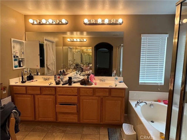 bathroom with a garden tub, tile patterned flooring, double vanity, and a sink