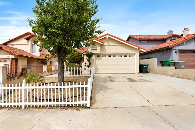 view of front of property with concrete driveway, an attached garage, a fenced front yard, and stucco siding
