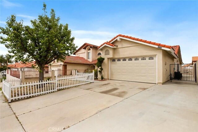 13139 Kiowa Dr, Moreno Valley, CA 92553 - mediterranean / spanish-style home featuring an attached garage, concrete driveway, a fenced front yard, and stucco siding