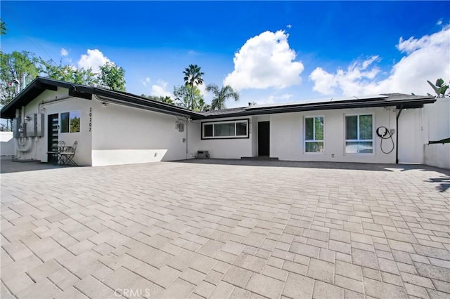 view of front of property featuring solar panels, a patio area, and stucco siding