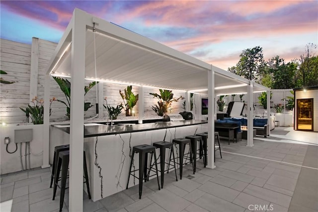 patio terrace at dusk with an outdoor hangout area, outdoor dry bar, and fence private yard