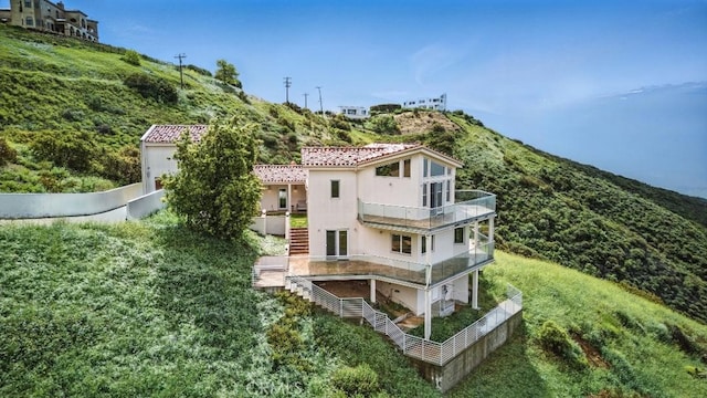 view of side of home featuring a mountain view, a balcony, and stucco siding