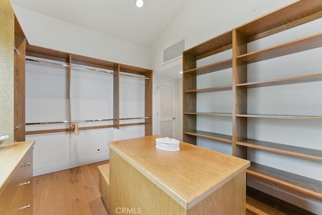 spacious closet with visible vents, vaulted ceiling, and light wood-type flooring