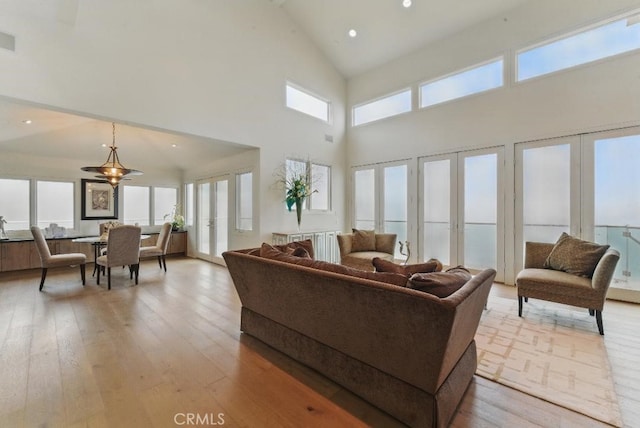 living area with high vaulted ceiling, light wood-style floors, and plenty of natural light