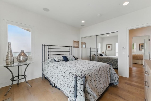 bedroom featuring baseboards, light wood-style flooring, recessed lighting, and a closet