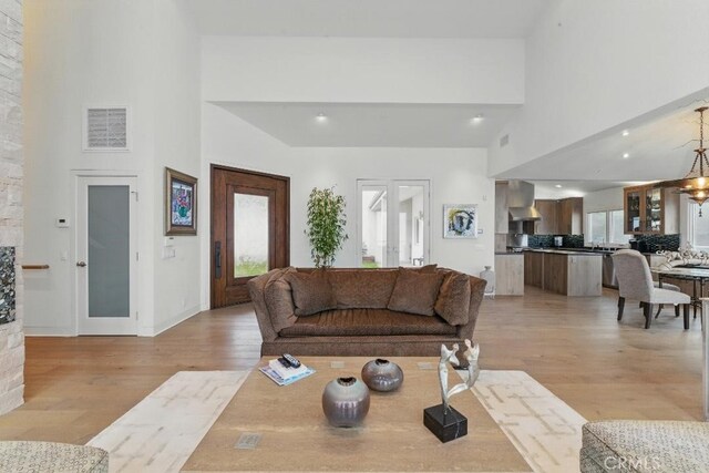 living area with visible vents, light wood-style flooring, and a high ceiling