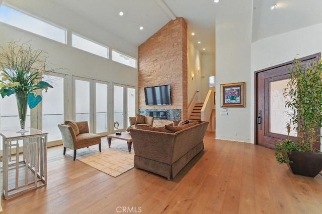 living area featuring stairway, light wood-style flooring, and high vaulted ceiling