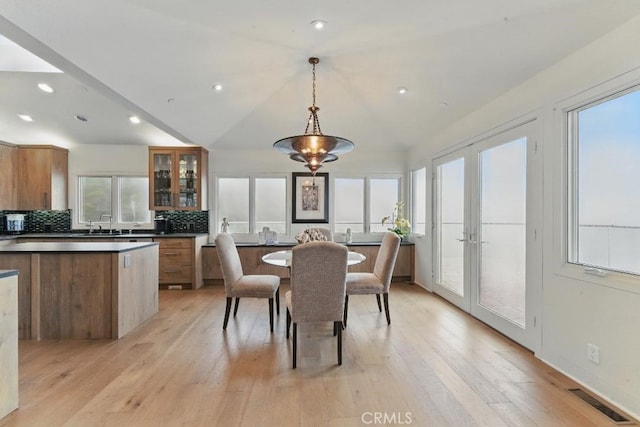 dining space with lofted ceiling, visible vents, french doors, and light wood-style floors