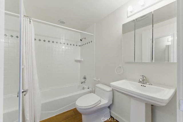 bathroom with wood finished floors, shower / bath combo with shower curtain, and toilet