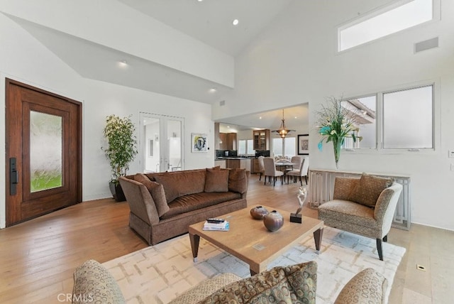 living room with visible vents, light wood-type flooring, a high ceiling, and recessed lighting