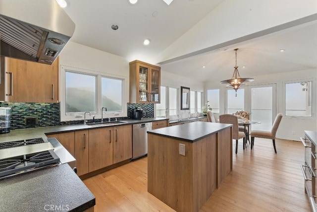 kitchen featuring stainless steel dishwasher, a sink, dark countertops, a center island, and ventilation hood