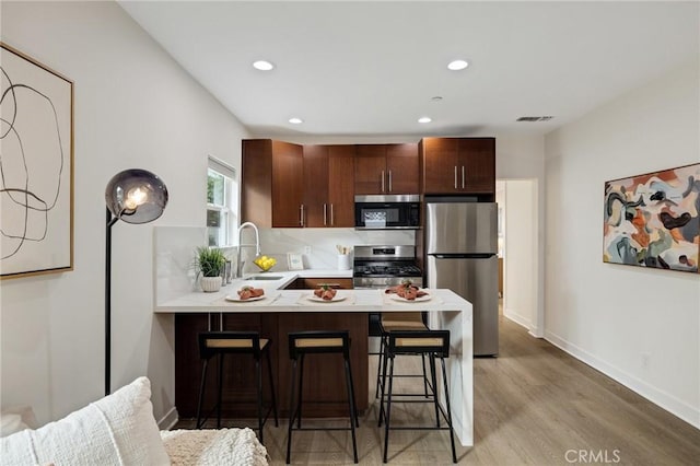 724 San Miguel Ave, Venice, CA 90291 - kitchen with a breakfast bar area, light wood-style flooring, appliances with stainless steel finishes, light countertops, and a peninsula