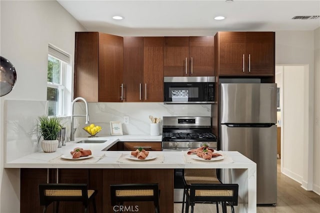 724 San Miguel Ave, Venice, CA 90291 - kitchen with decorative backsplash, stainless steel appliances, a sink, a peninsula, and a kitchen breakfast bar