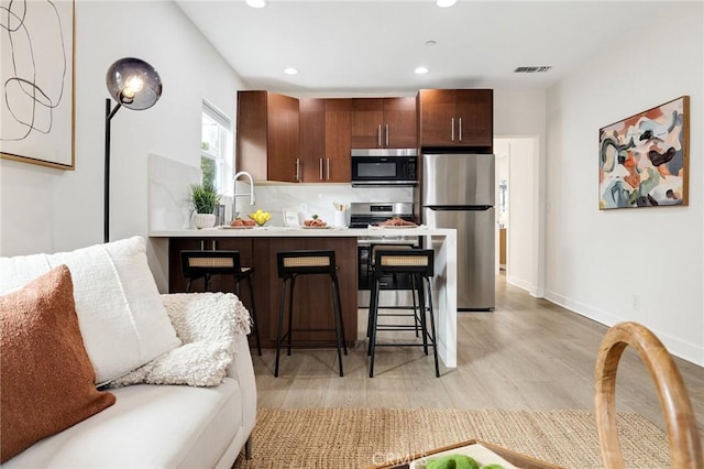 724 San Miguel Ave, Venice, CA 90291 - kitchen featuring appliances with stainless steel finishes, a breakfast bar, visible vents, light wood-style floors, and recessed lighting