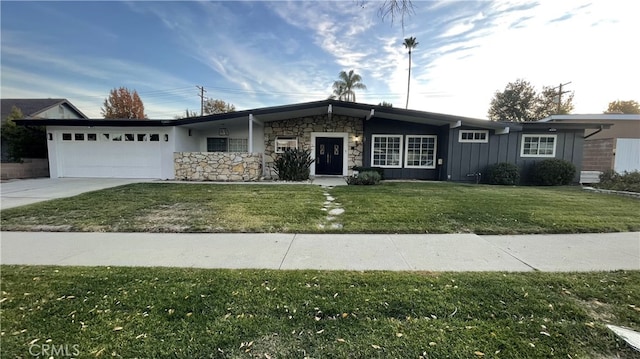ranch-style home with board and batten siding, a front yard, concrete driveway, an attached garage, and stone siding