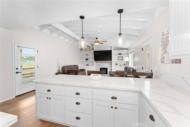 8051 Los Altos Dr, Los Molinos, CA 96055 - kitchen with beamed ceiling, ceiling fan, light wood finished floors, a glass covered fireplace, and white cabinetry