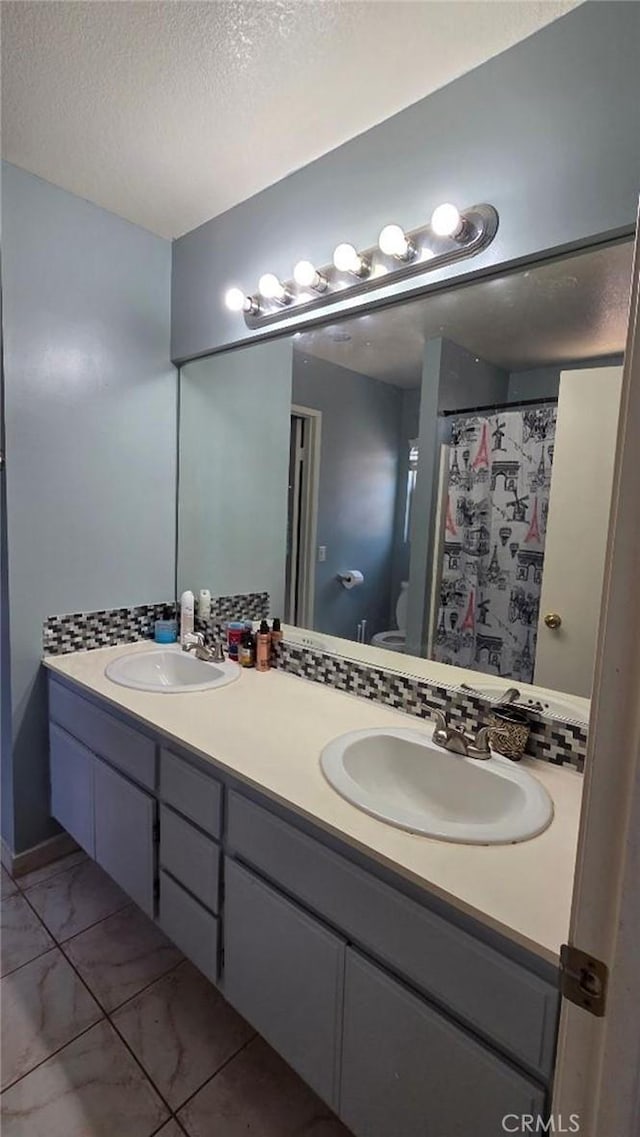 39557 Warbler Dr, Temecula, CA 92591 - bathroom featuring marble look tiles, a textured ceiling, double vanity, toilet, and a shower with shower curtain