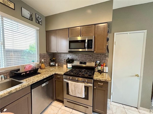 39557 Warbler Dr, Temecula, CA 92591 - kitchen featuring stainless steel appliances, tasteful backsplash, light stone countertops, and dark brown cabinets