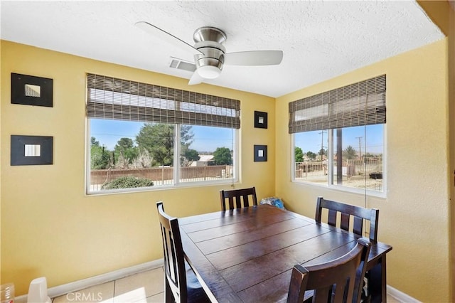 dining space featuring a textured ceiling, a ceiling fan, and baseboards