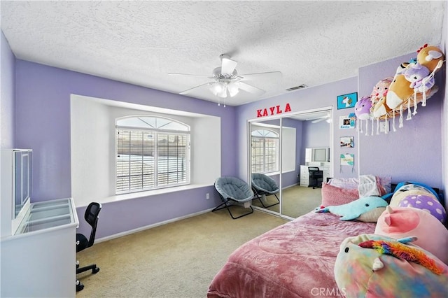 carpeted bedroom with a closet, baseboards, visible vents, a ceiling fan, and a textured ceiling