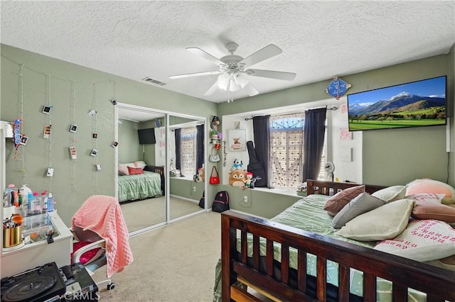 carpeted bedroom featuring a textured ceiling, visible vents, ceiling fan, and a closet