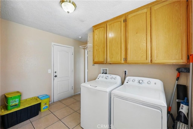 clothes washing area featuring light tile patterned floors, separate washer and dryer, cabinet space, and a textured ceiling