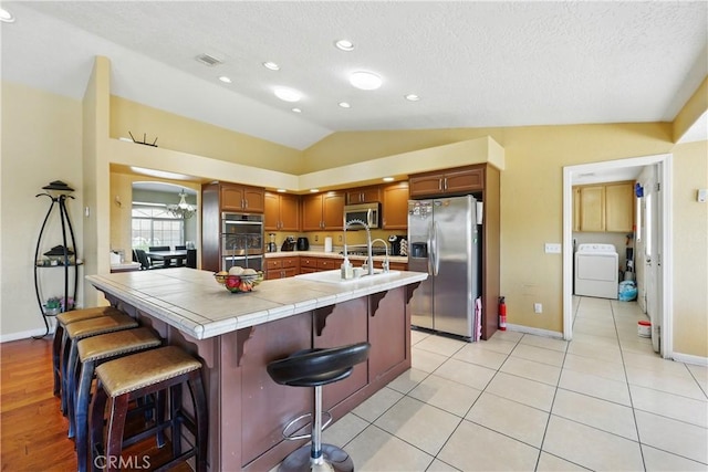 15710 Rimrock Rd, Apple Valley, CA 92307 - kitchen featuring a kitchen breakfast bar, stainless steel appliances, tile countertops, washer / dryer, and vaulted ceiling