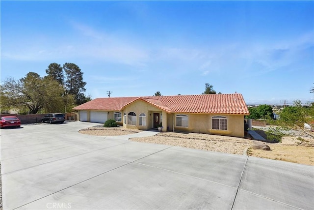 view of front facade with driveway, a garage, stucco siding, and a tiled roof