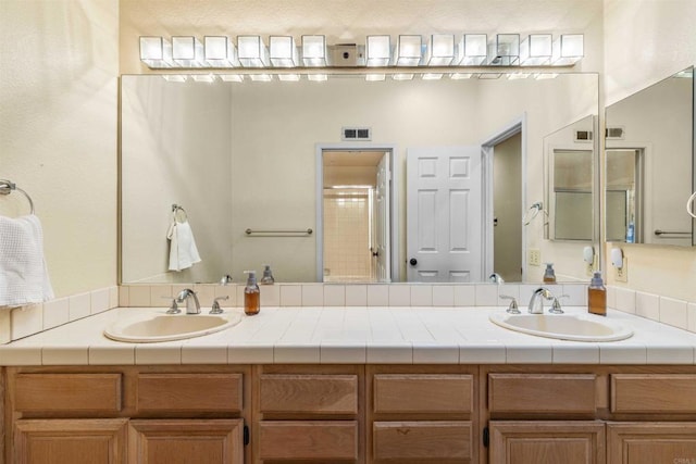 bathroom with visible vents, double vanity, and a sink