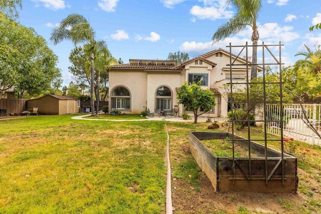 back of house featuring a lawn, a storage unit, stucco siding, and a fenced backyard