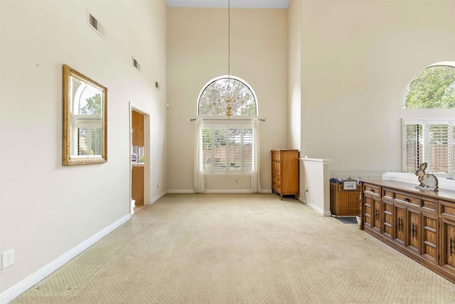 interior space with a towering ceiling, plenty of natural light, and light carpet