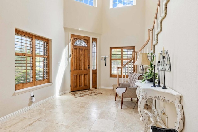 entrance foyer with a towering ceiling, light tile patterned floors, and baseboards