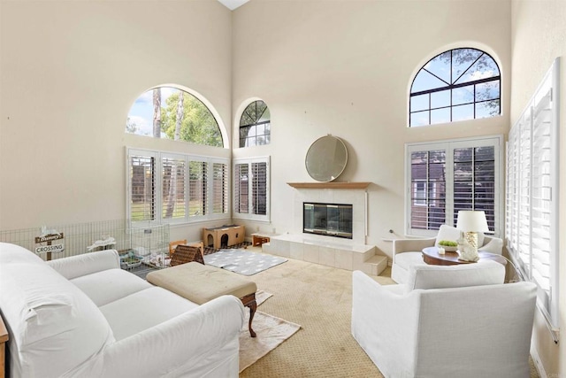 carpeted living area featuring a towering ceiling and a tiled fireplace