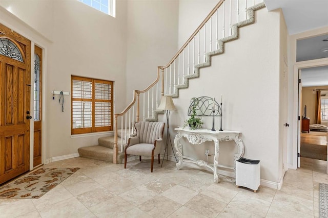 foyer entrance with baseboards, stairs, and plenty of natural light
