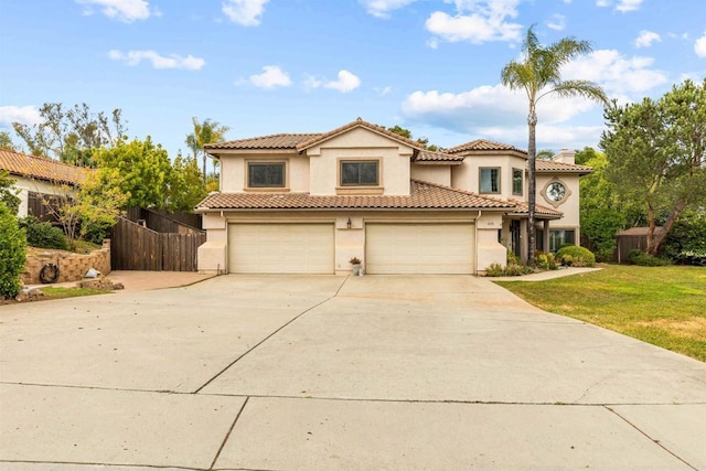 mediterranean / spanish-style house featuring a front lawn, driveway, stucco siding, and fence