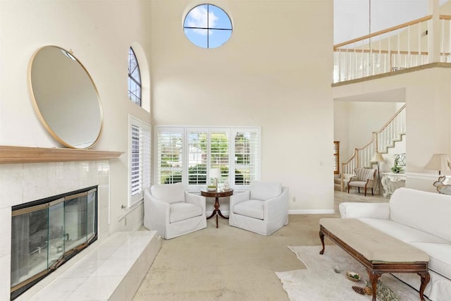 living room with a towering ceiling, stairs, baseboards, and a fireplace