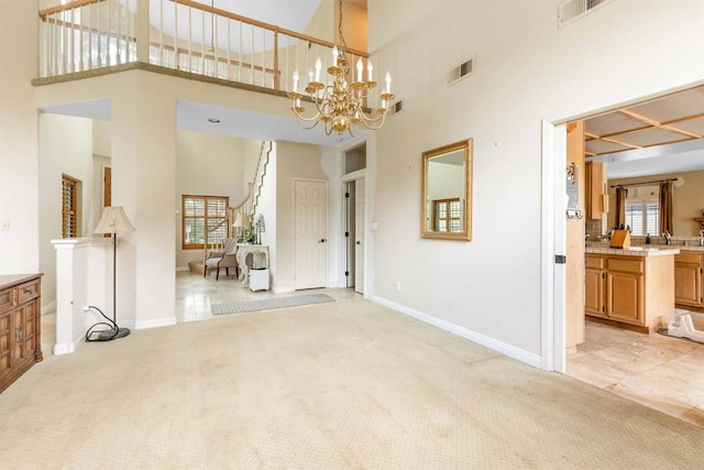 unfurnished living room with a towering ceiling, visible vents, baseboards, and light carpet