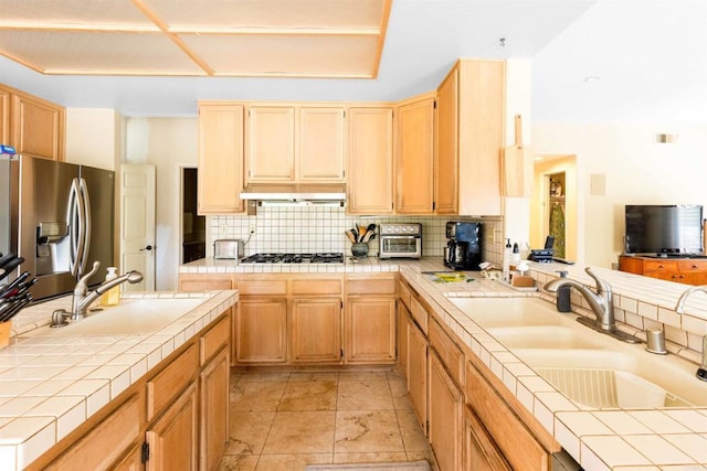 kitchen featuring a sink, stainless steel appliances, tasteful backsplash, and tile countertops